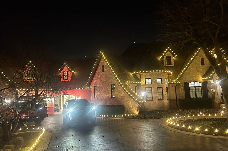 Stone and brick estate with roofline and driveway lighting