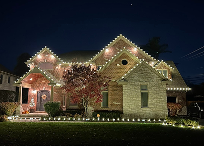 Brick and stone home with warm-white roofline, window and landscape lighting