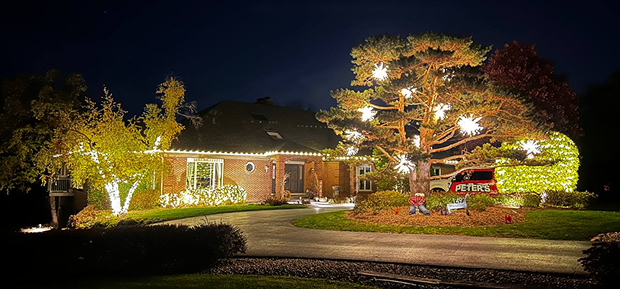 Brick home with illuminated trees, shrubs and roofline lighting
