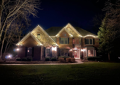 Two-story brick home with warm-white roofline and entry lighting