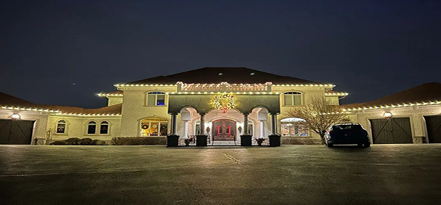 Symmetrical estate with warm-white roofline lights and a wreath over the entrance